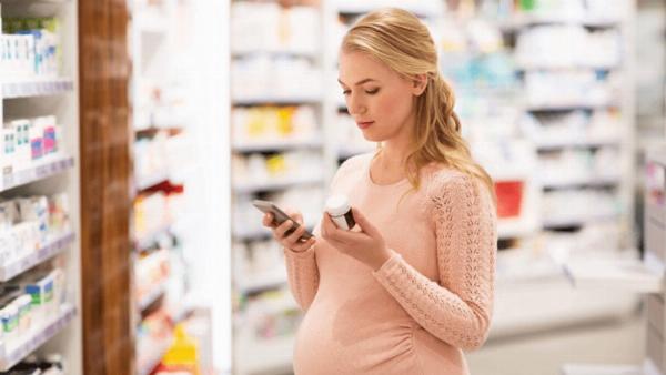 Hình ảnh mẹ bầu đang cẩn thận đọc bảng thành phần của lăn nách, tập trung vào các chất như Aluminum và Paraben