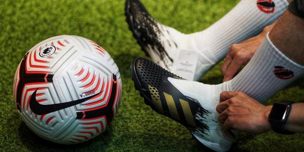 Một người đang lau chùi đôi giày Nike Flyknit bằng bàn chải lông mềm và dung dịch vệ sinh chuyên dụng, thể hiện quy trình bảo quản giày tại nhà