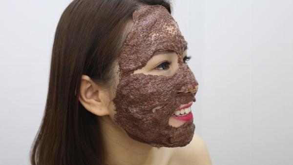 Một người phụ nữ trẻ đang đắp mặt nạ hạt ngũ hoa lên mặt, tập trung vào vùng da mụn và viêm