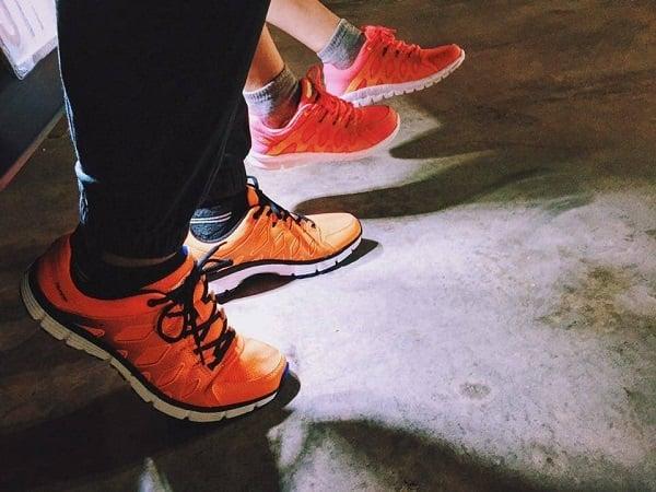 Một người đang cẩn thận vệ sinh đôi giày thể thao màu trắng bằng bàn chải mềm và dung dịch chuyên dụng, tập trung vào việc bảo quản giày sau khi mua tại Aeon Mall Bình Dương.